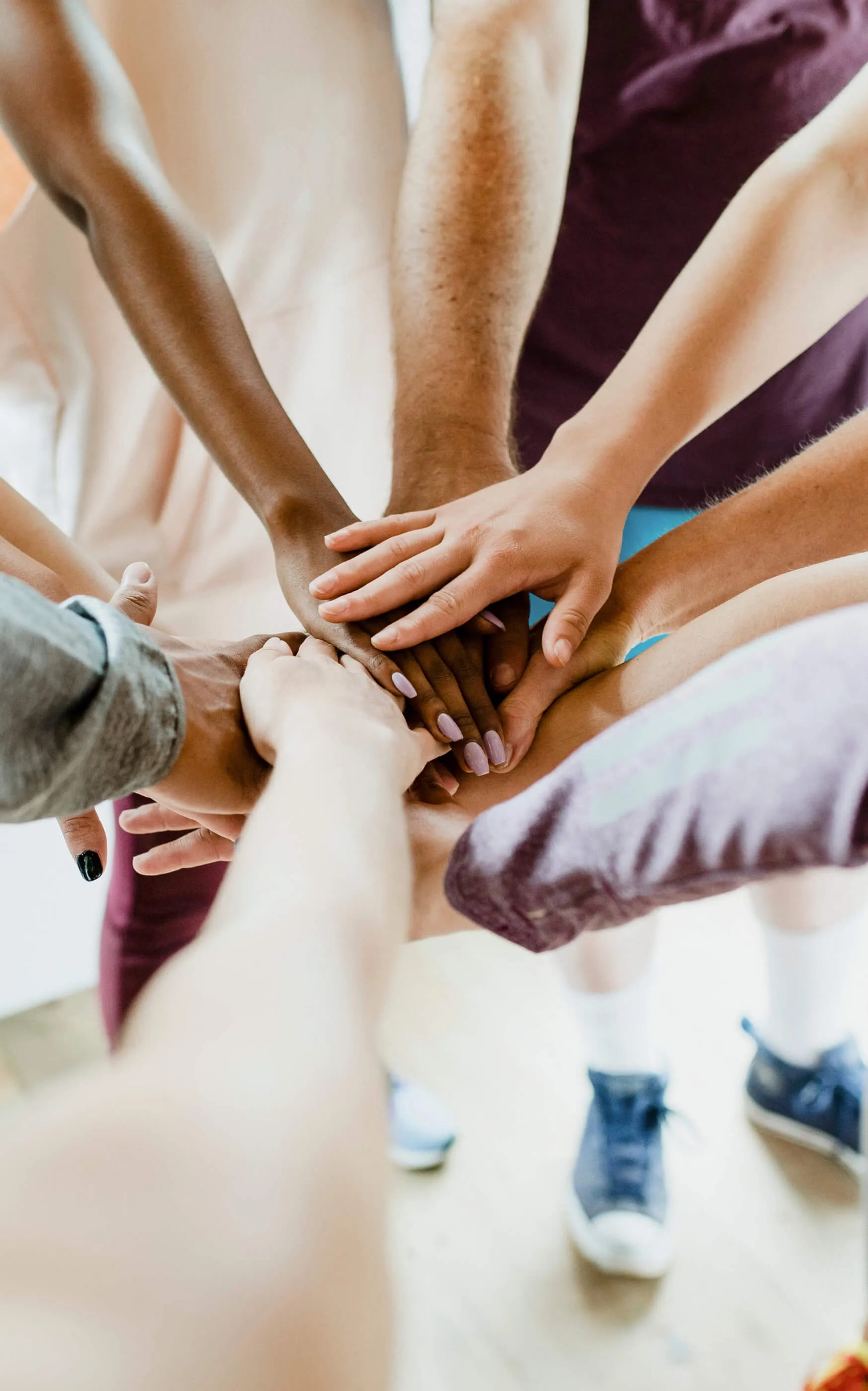 Diverse Southern Coast Services team members stacking their hands together in a circle, showing teamwork and unity